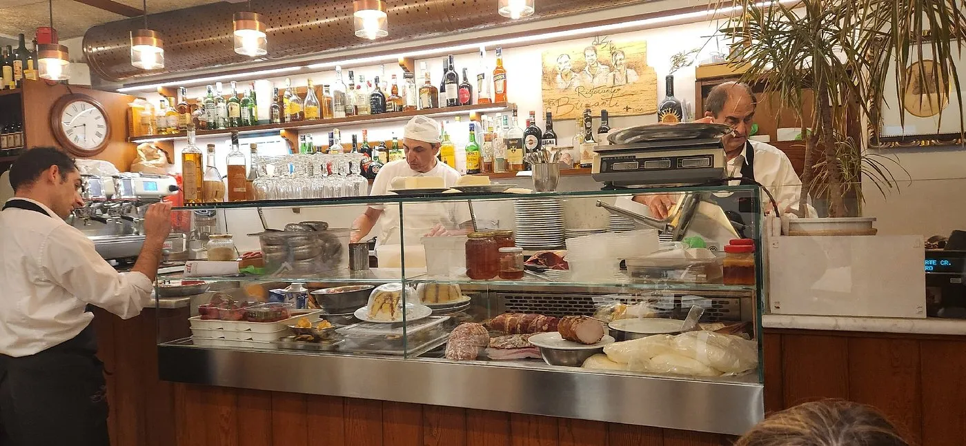 Il bancone con la cucina a vista, lo staff al lavoro e l'insegna dipinta coi ritratti dei fratelli Briganti