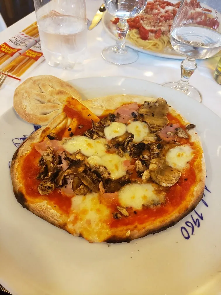 Pizza sottile ai funghi e prosciutto, nel piatto con la scritta &laquo;dal 1960&raquo;