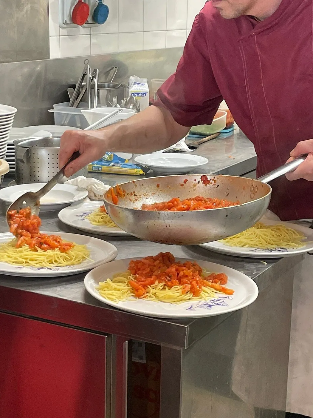Il pomodoro fresco versato dalla padella sugli spaghettini, sui piatti della casa